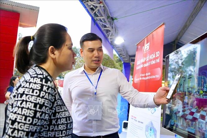 Nhân viên gian hàng hướng dẫn du khách thao tác thiết bị VR nhằm trải nghiệm mô phỏng hành trình khám phá các điểm du lịch. Ảnh: Lan Anh/TTXVN phát