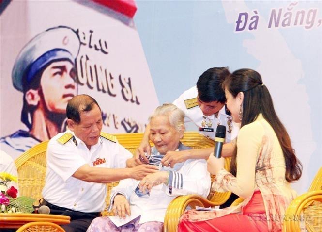 Bà Lê Thị Muộn, mẹ của Liệt sĩ Phan Văn Sự, người đã hy sinh anh dũng trong trận chiến bảo vệ Gạc Ma năm 1988, mặc chiếc áo - kỷ vật duy nhất còn lại của người con trai, tại chương trình giao lưu “Hướng về Trường Sa thân yêu”, ngày 14/3/2013. Ảnh: Trần Lê Lâm - TTXVN