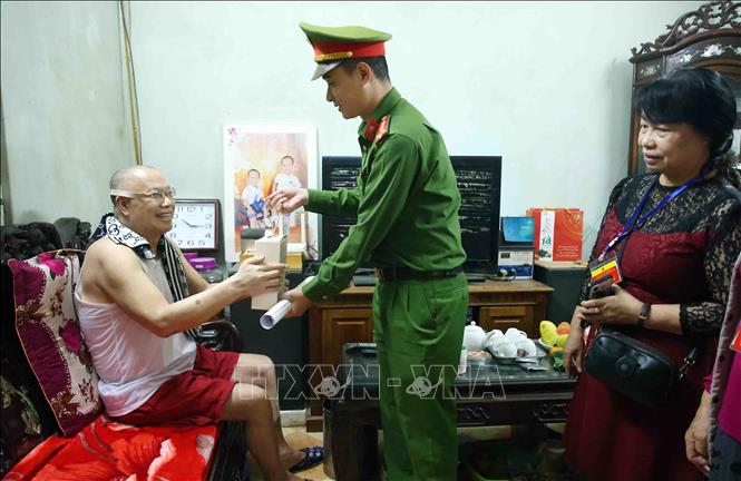 Cán bộ, chiến sĩ Công an phường Ngọc Hà đến nhà thăm hỏi các cử tri có sức khoẻ yếu không thể đi lại được, đồng thời phổ biến những quy định, giới thiệu danh sách và tóm tắt tiểu sử của người ứng cử đại biểu Quốc hội và HĐND các cấp. Ảnh: Phạm Kiên - TTXVN
