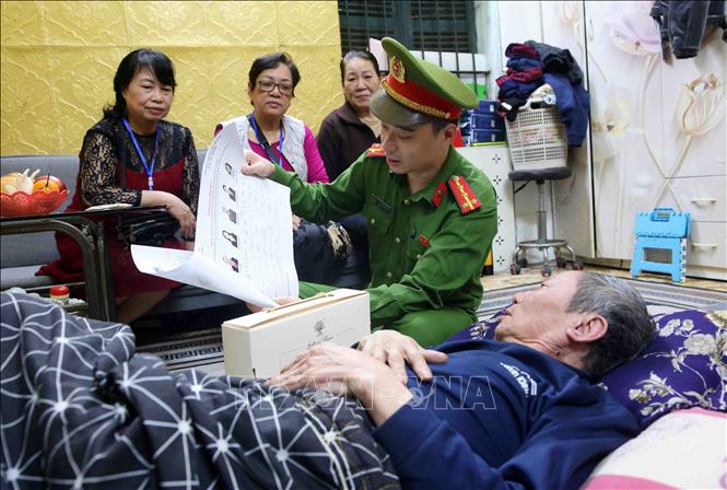 Cán bộ, chiến sĩ Công an phường Ngọc Hà đến nhà thăm hỏi các cử tri có sức khoẻ yếu không thể đi lại được, đồng thời phổ biến những quy định, giới thiệu danh sách và tóm tắt tiểu sử của người ứng cử đại biểu Quốc hội và HĐND các cấp. Ảnh: Phạm Kiên - TTXVN
