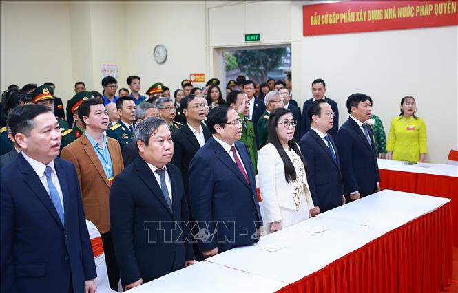 Thủ tướng Phạm Minh Chính và Phu nhân cùng các cử tri thực hiện nghi thức chào cờ, khai mạc bầu cử tại Khu vực bỏ phiếu số 21 phường Tây Hồ, thành phố Hà Nội. Ảnh: Dương Giang-TTXVN 
