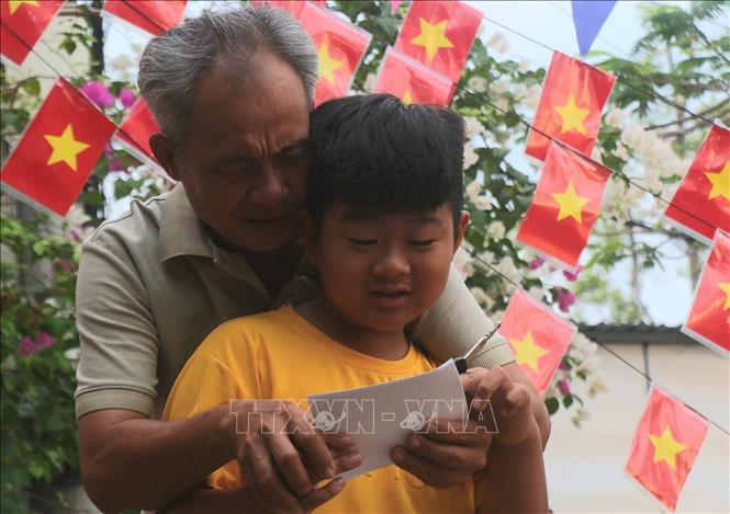 Cử tri Nguyễn Văn Đủ cùng cháu đi bầu cử tại điểm bỏ phiếu số 4, phường Vị Tân, thành phố Cần Thơ. Ảnh: Duy Khương - TTXVN