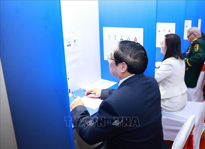 Thủ tướng Phạm Minh Chính tìm hiểu tiểu sử người ứng cử tại Khu vực bỏ phiếu số 21 phường Tây Hồ, thành phố Hà Nội. Ảnh: Dương Giang-TTXVN 
