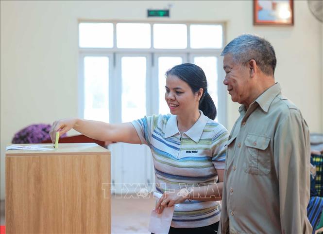 Bác sĩ Phạm Thị Pha - Phó trưởng phòng y tế Trung tâm Điều dưỡng thương binh Thuận Thành hỗ trợ thương binh Nguyễn Văn Đáp (thương binh có tỉ lệ thương tật 81%, mất cả 2 tay) bỏ phiếu. Ảnh: Hoàng Hiếu - TTXVN