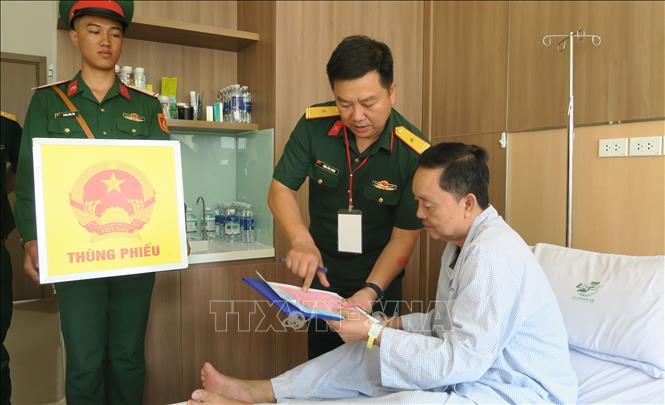 Tổ giúp việc bầu cử tại điểm bầu cử số 055 phường Hạnh Thông đặt tại Bệnh viện Quân y 175 hướng dẫn cử tri là bệnh nhân bỏ phiếu bầu cử. Ảnh: Đinh Hằng - TTXVN