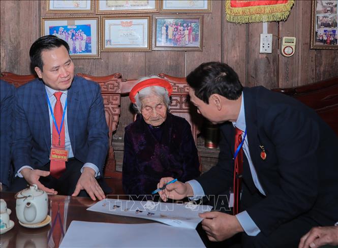 Cán bộ phường Phúc Lợi trực tiếp hỗ trợ, giới thiệu danh sách người ứng cử cho cử tri Chu Thị Nhớn, 102 tuổi, cử tri cao tuổi thuộc gia đình có công với cách mạng. Dù tuổi cao, cụ vẫn phấn khởi thực hiện quyền bầu cử, thể hiện tinh thần trách nhiệm công dân. Ảnh: Phan Phương – TTXVN