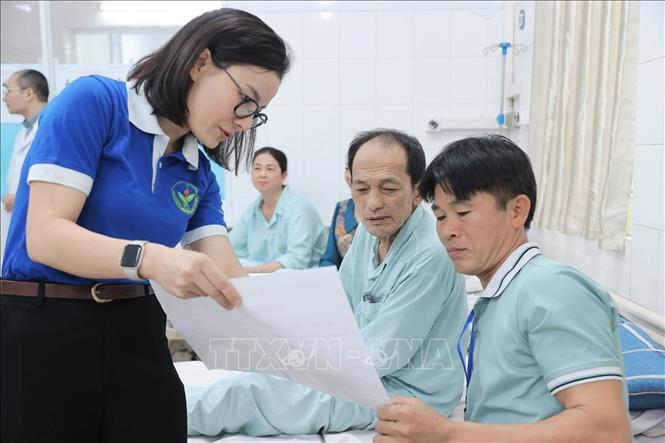 Đoàn viên thanh niên Bệnh viện Việt Đức hướng dẫn người nhà bệnh nhân và bệnh nhân về quy định bầu cử tại điểm bầu cử lưu động Bệnh viện Hữu nghị Việt Đức. Ảnh: Minh Quyết - TTXVN