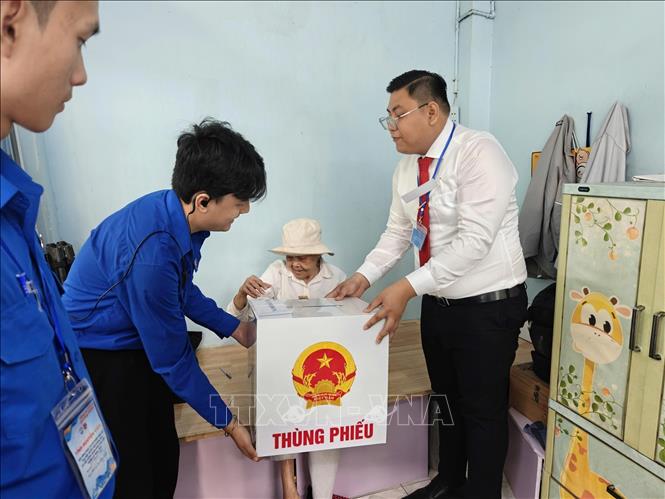 Tổ bầu cử Khu vực bỏ phiếu số 2, Khu phố 7, phường Xuân Hoà hỗ trợ bà Nguyễn Thị Liễu (82 tuổi) hoàn thành việc bỏ phiếu. Ảnh: Hứa Chung-TTXVN
