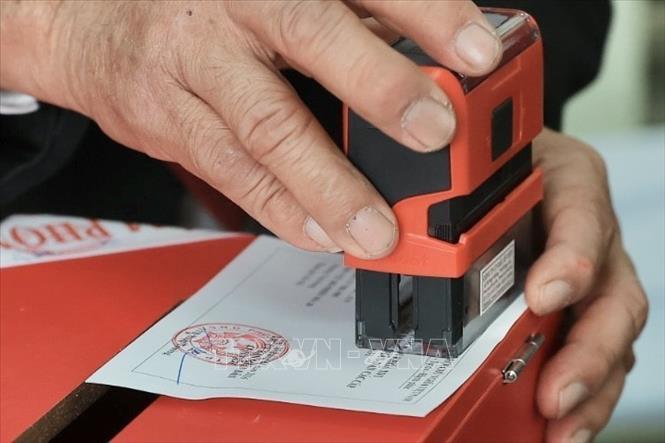 Thành viên tổ bầu cử đóng dấu hoàn thành bỏ phiếu lên thẻ cử tri. Ảnh: Minh Quyết - TTXVN