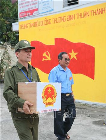 Thành viên Tổ bầu cử số 10, Ban bầu cử số 3 đưa hòm phiếu phụ đến tận nơi ở của các thương binh nặng đang sinh sống tại Trung tâm điều dưỡng thương binh Thuận Thành. Ảnh: Hoàng Hiếu - TTXVN