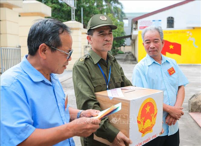 Thành viên Tổ bầu cử số 10, Ban bầu cử số 3 đưa hòm phiếu phụ đến tận nơi ở của các thương binh nặng đang sinh sống tại Trung tâm điều dưỡng thương binh Thuận Thành. Ảnh: Hoàng Hiếu - TTXVN 