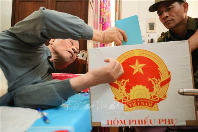 Cử tri Đỗ Văn Thế (sinh năm 1944, thương binh hạng ¼, tỷ lệ thương tật 91%) thực hiện bỏ phiếu vào hòm phiếu phụ. Ảnh: Hoàng Hiếu - TTXVN