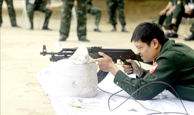 Giáo viên tham gia nội dung thi bắn súng tiểu liên AK bằng máy bắn tập. Ảnh: Hoàng Hùng - TTXVN