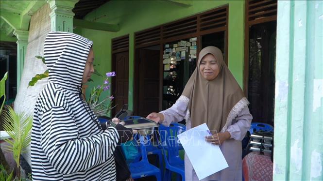 Nhân viên của Trạm y tế Posyandu trao hộp đồ ăn cho một phụ nữ trong diện được nhận hỗ trợ. Ảnh: Đỗ Quyên – PV TTXVN tại Indonesia