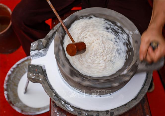 Công đoạn xay gạo bằng cối đá truyền thống. Ảnh: Khánh Hoà - TTXVN