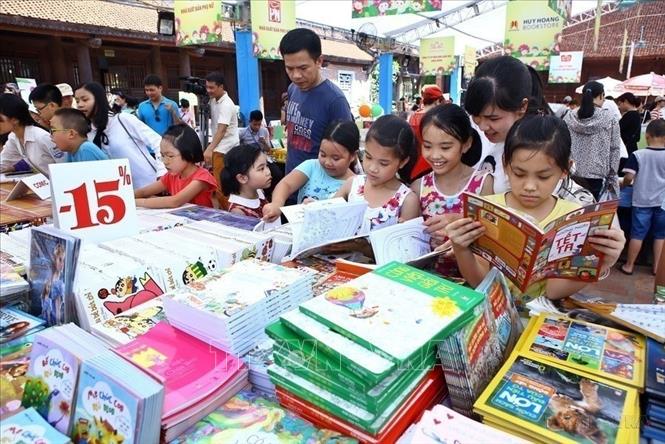 Các em thiếu nhi hào hứng cùng gia đình chọn cho mình cuốn sách ưng ý tại Hội sách thiếu nhi. Ảnh: Minh Quyết - TTXVN