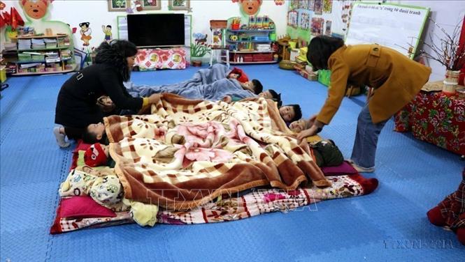 Giáo viên trường Mầm non xã Xuân Vân (Yên Sơn, Tuyên Quang) chủ động giữ ấm cho học sinh trước thời tiết giá rét. Ảnh: Quang Cường - TTXVN