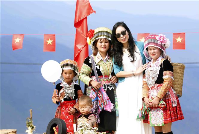 Du khách thích thú khi chụp ảnh cùng đồng bào dân tộc Mông tại bản Nậm Nghẹp, xã Ngọc Chiến trong Ngày hội hoa sơn tra năm 2026. Ảnh: Quang Quyết - TTXVN