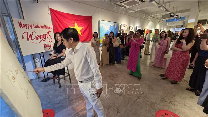 Họa sĩ Phương Quốc Trí thực hiện bức chân dung cho “người mẫu” là một khách mời trong sự kiện. Ảnh: Việt Dũng - P/v TTXVN tại Singapore