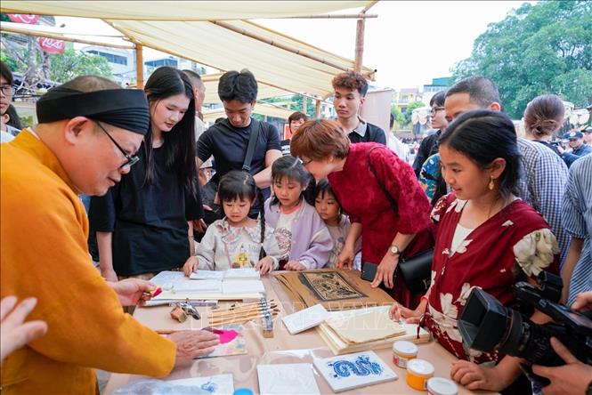 Người dân tìm hiểu về dòng tranh dân gian Hàng Trống. Ảnh: Khánh Hoà - TTXVN