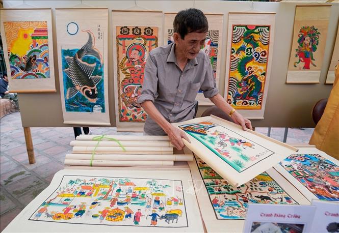 Nghệ nhân tranh dân gian Hàng Trống Lê Đình Nghiêm giới thiệu các tác phẩm. Ảnh: Khánh Hoà - TTXVN