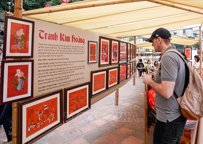Du khách nước ngoài tìm hiểu về tranh dân gian Kim Hoàng. Ảnh: Khánh Hoà - TTXVN