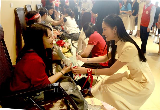 Á hậu 1 cuộc thi Hoa hậu Quốc gia Việt Nam 2024 Đỗ Thị Phương Thanh tặng hoa động viên tình nguyện viên tham gia hiến máu tại Chương trình. Ảnh: Ảnh: Hoàng Hùng - TTXVN