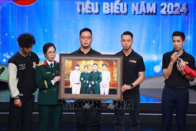 Phùng Quang Trung, gương mặt trẻ Việt Nam tiêu biểu năm 2024 và nhóm phục dựng ảnh Skyline trao bức ảnh phục dựng cho gia đình liệt sĩ Tăng Bá Hưng. Nhóm đã phục dựng hàng nghìn bức ảnh liệt sĩ nhằm tri ân những người đã hy sinh vì độc lập, tự do của Tổ quốc, góp phần cùng xã hội thực hiện nghĩa cử “Đền ơn đáp nghĩa”. Ảnh: Dương Giang -  TTXVN