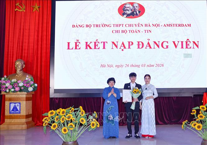 Bí thư Đảng ủy, Hiệu trưởng Trường THPT chuyên Hà Nội – Amsterdam Trần Thùy Dương trao quyết định kết nạp Đảng cho học sinh Trần Đức Anh. Ảnh: Thanh Tùng - TTXVN