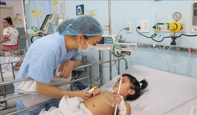 Nhân viên y tế Bệnh viện Nhi đồng 1 Thành phố Hồ Chí Minh chăm sóc bệnh nhi mắc tay chân miệng. Ảnh: Đinh Hằng - TTXVN