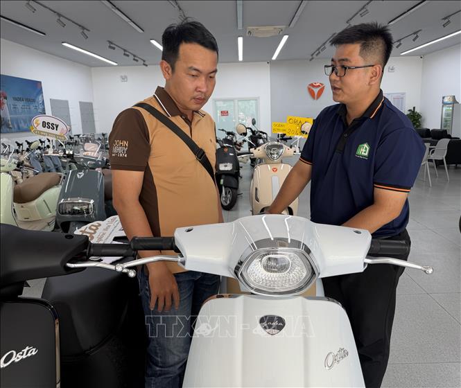 Nhân viên hàng Cửa hàng Yadea Cái Răng, đường Võ Nguyên Giáp, phường Hưng Phú, thành phố Cần Thơ tư vấn bán hàng cho một khách hàng về xe máy điện Osta H+. Ảnh: Nguyễn Văn Việt -TTXVN
