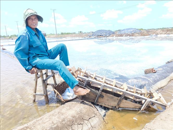 Ông Võ Văn Lực, xã Bảo Thạnh, tỉnh Vĩnh Long, cho nước vào khuôn sản xuất muối. Ảnh: Huỳnh Phúc Hậu - TTXVN