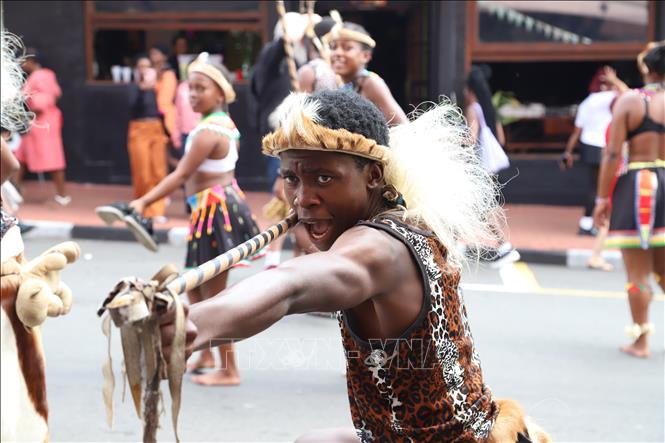 Các nghệ sĩ Zulu trong trang phục đính lông thú đặc trưng, vòng cổ hạt cườm lung linh, lông vũ lấp lánh và khiên truyền thống đã khiến cả con phố rung chuyển theo nhịp trống dồn dập và tiếng hát vang vọng. Ảnh: Hồng Minh - PV TTXVN tại Nam Phi