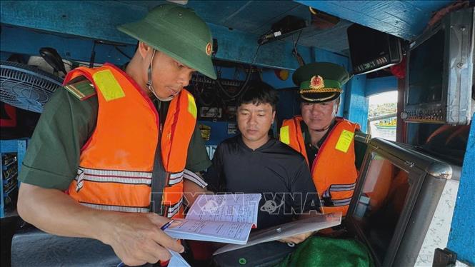 Bộ đội biên phòng Quảng Ngãi kiểm tra giấy tờ, thủ tục trước khi tàu cá xuất bến tuyên truyền và đề nghị ngư dân viết cam kết chấp hành các quy định về khai thác IUU. Ảnh: TTXVN phát
