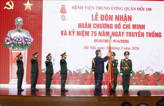 Tổng Bí thư Tô Lâm, Bí thư Quân ủy Trung ương gắn Huân chương Hồ Chí Minh lên Quân kỳ Quyết thắng của Bệnh viện Trung ương Quân đội 108. Ảnh: Thống Nhất – TTXVN