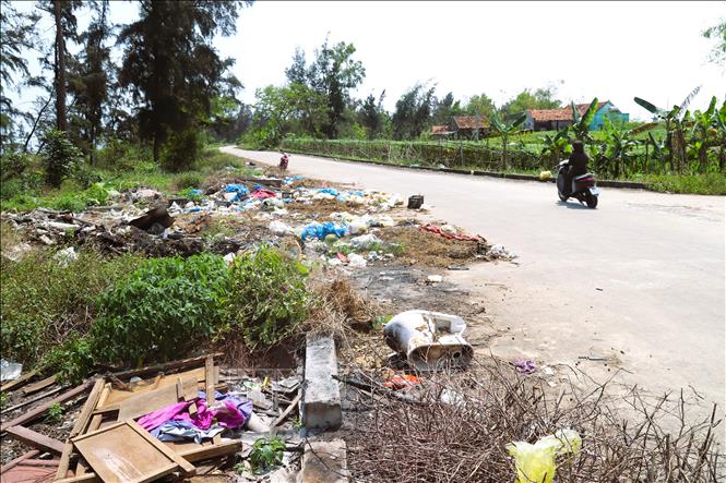Rác thải được đổ tràn lan, chiếm dụng lòng đường trên tuyến đê biển qua địa bàn xã Quỳnh Phú (tỉnh Nghệ An). Ảnh: Xuân Tiến - TTXVN 