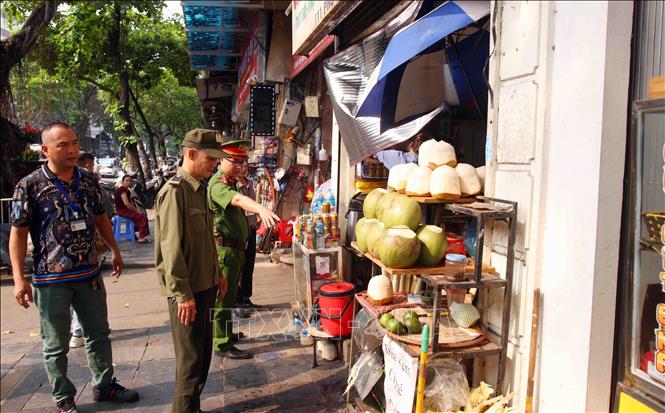 Tổ công tác của Công an phường Hoàn Kiếm xử lý vi phạm về trật tự đô thị tại phố Phủ Doãn. Ảnh: Phạm Kiên - TTXVN