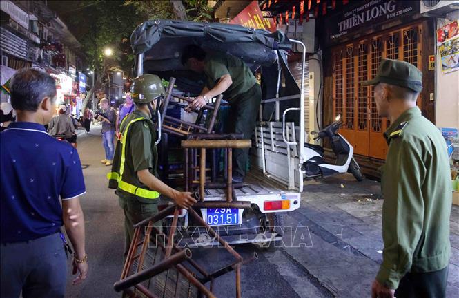 Tại phố Nguyễn Siêu, nhiều trường hợp vi phạm đã bị lập biên bản xử phạt; các vật dụng như ô dù, biển quảng cáo, bàn ghế đặt sai quy định bị thu giữ. Ảnh: Phạm Kiên - TTXVN