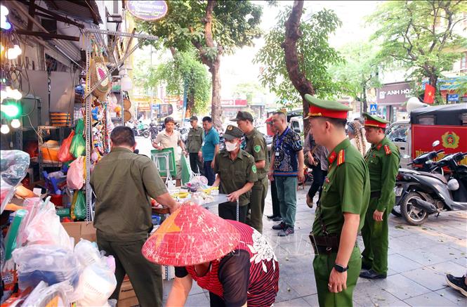 Tổ công tác của Công an phường Hoàn Kiếm xử lý vi phạm về trật tự đô thị tại phố Trần Phú. Ảnh: Phạm Kiên - TTXVN
