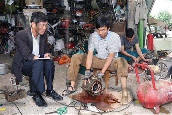 Nạn nhân bom mìn Trương Hồng Hoàn (sinh năm 1984), ở thôn Tây, xã Hiền Ninh, huyện Quảng Ninh, tỉnh Quảng Bình (giữa ảnh) vươn lên trong cuộc sống với nghề điện. Ảnh: Anh Tuấn - TTXVN