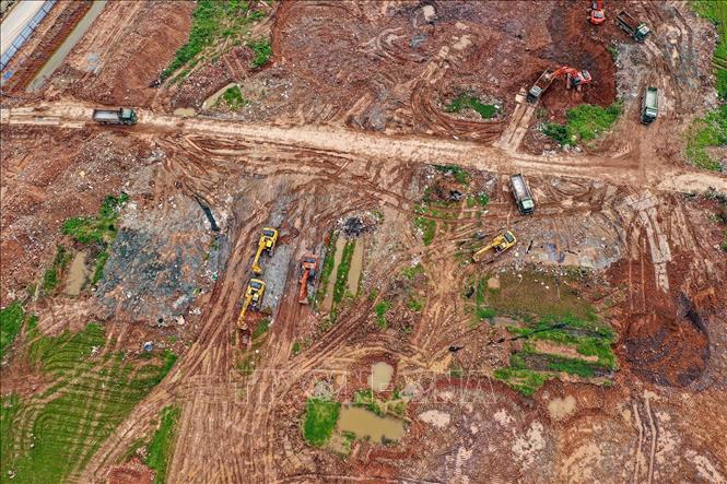 Máy móc hạng nặng san gạt, nạo vét lòng hồ; xe tải vận chuyển đất nối đuôi nhau ra vào khu vực thi công. Ảnh: Trung Nguyên - TTXVN