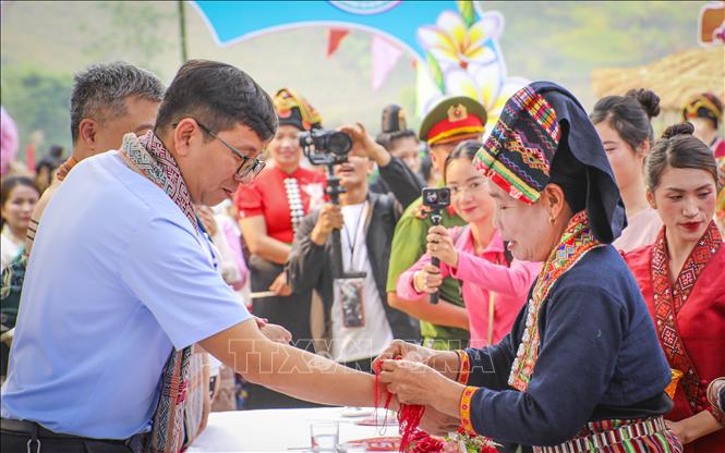 Nghi thức buộc chỉ cổ tay, cầu may trong Lễ hội Tết Té nước. Ảnh: Xuân Tư - TTXVN