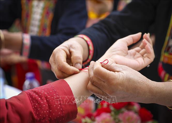 Nghi thức buộc chỉ cổ tay, cầu may trong Lễ hội Tết Té nước. Ảnh: Xuân Tư - TTXVN
