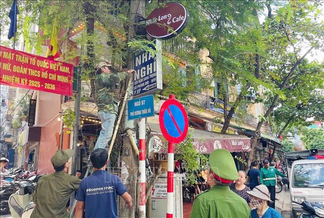 Lực lượng chức năng phường Phương Liệt tổ chức tháo dỡ biển quảng cáo đặt sai quy định tại ngõ 97 phố Vương Thừa Vũ (khu vực giáp ranh giữa hai phường). Ảnh: Phạm Kiên - TTXVN 
