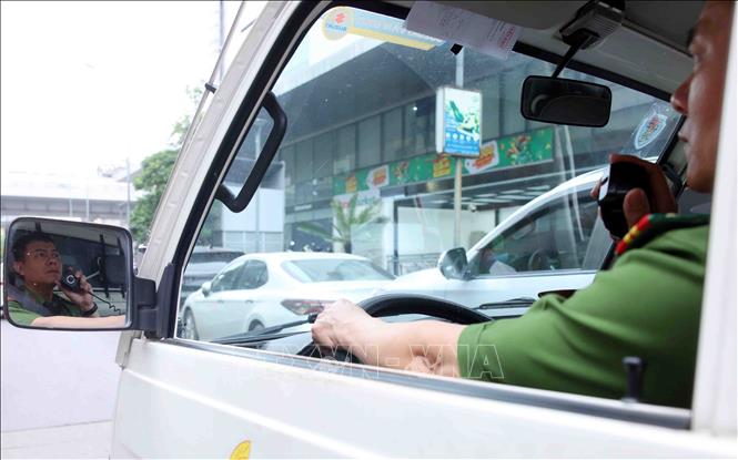Công an phường Phương Liệt phát loa nhắc nhở các phương tiện giao thông dừng, đỗ sai quy định trên phố Lê Trọng Tấn. Ảnh: Phạm Kiên - TTXVN