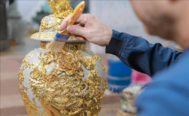Công đoạn dát vàng thủ công được thực hiện tỉ mỉ, từng lớp vàng kim tạo nên sắc ánh rực rỡ cho sản phẩm. Ảnh: Phan Phương – TTXVN
