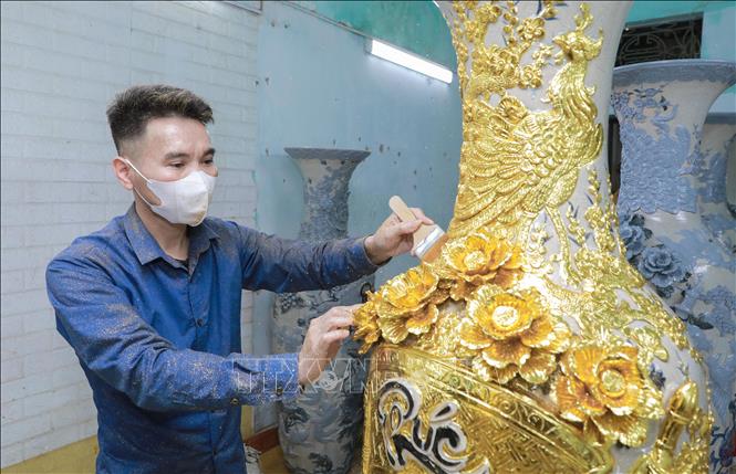 Công đoạn dát vàng thủ công được thực hiện tỉ mỉ, từng lớp vàng kim tạo nên sắc ánh rực rỡ cho sản phẩm. Ảnh: Phan Phương – TTXVN