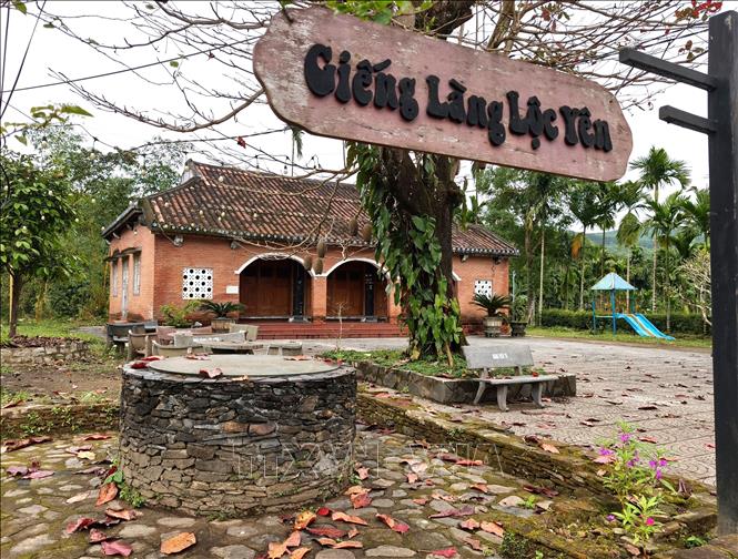 Giếng cổ và nhà đón tiếp du khách khi bước vào cổng làng Lộc Yên. Ảnh: Quốc Dũng - TTXVN