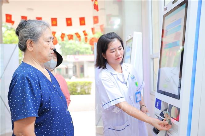 Nhân viên y tế phường Việt Hưng hướng dẫn người dân đăng ký khám bằng thẻ CCCD. Ảnh: Minh Quyết - TTXVN 