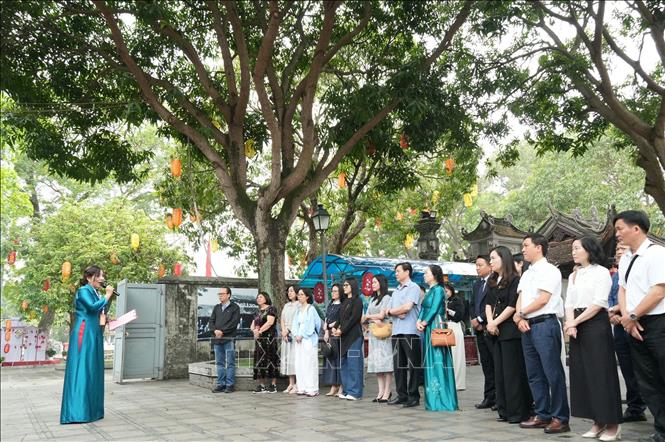 Du khách nghe hướng dẫn viên giới thiệu về Đền Đô, nơi thờ 8 vị Vua triều Lý. Ảnh: Đồng Thúy - TTXVN